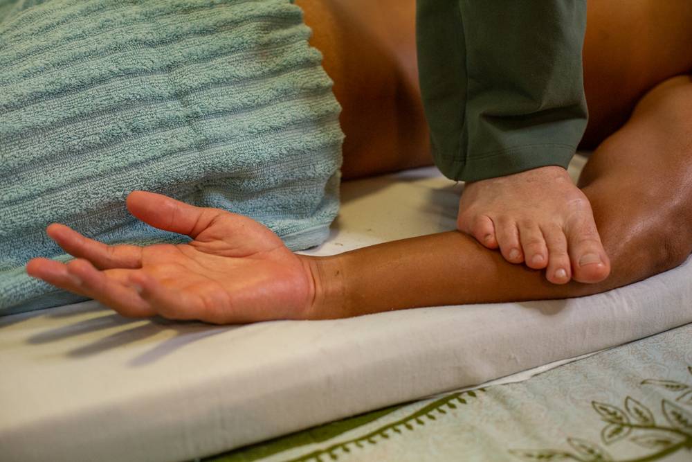 Detalhe do trabalho com os pés sobre a perna de quem recebe a sessão.